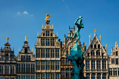 Low angle view of statue of building against blue sky