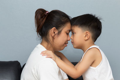 Side view of mother and son touching foreheads at home