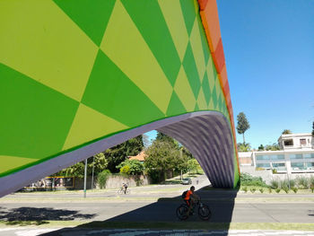 Man cycling on road in city against clear sky