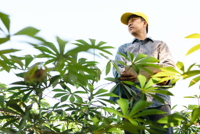 Low angle view of young man looking away against sky