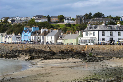 Houses on beach by buildings against sky