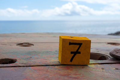 Close-up of information sign on beach against sky