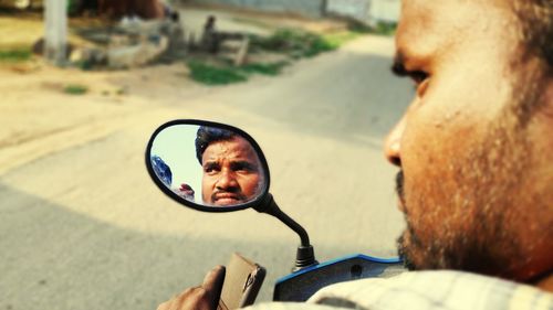 Reflection of man face in side-view mirror