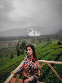 Portrait of beautiful young woman on land against sky