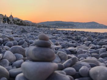 Stack of pebbles on beach against sky during sunset