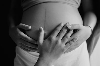 Hand touching the abdomen of a pregnant woman