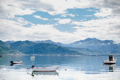 Boat moored on sea by mountains against sky