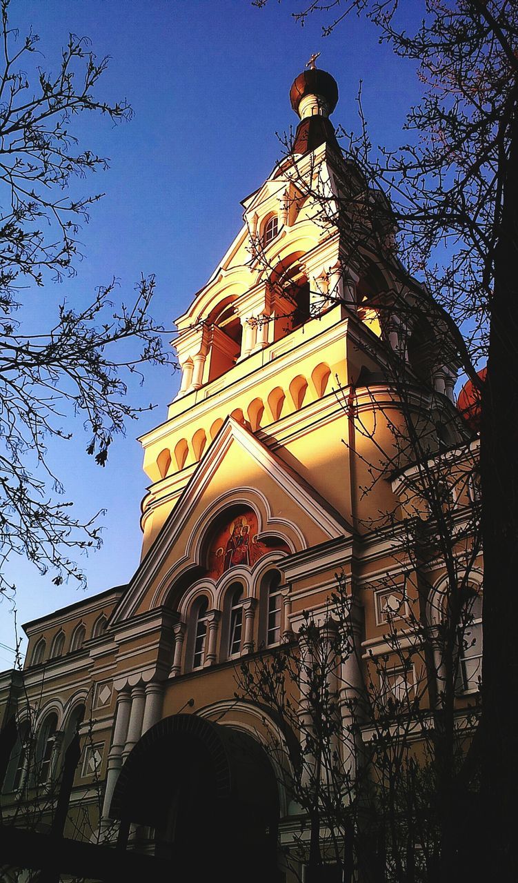 architecture, building exterior, built structure, low angle view, place of worship, religion, church, spirituality, clear sky, tower, tree, cathedral, famous place, clock tower, blue, travel destinations, history, sky