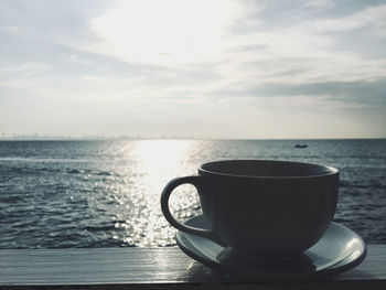 Close-up of coffee cup on table against sky