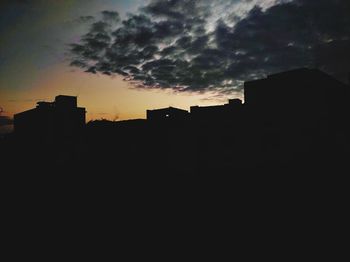 Low angle view of silhouette buildings against dramatic sky