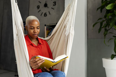 Woman sitting in hammock reading book