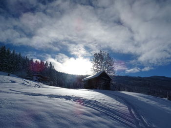 Snow covered landscape and houses against sky