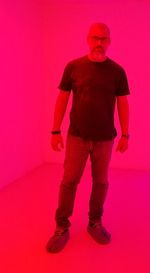 Full length portrait of man standing against pink background