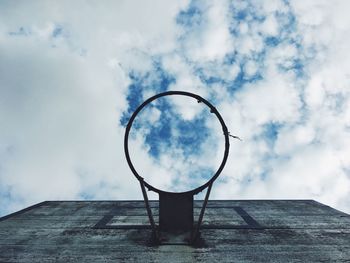 Low angle view of basketball hoop against cloudy sky