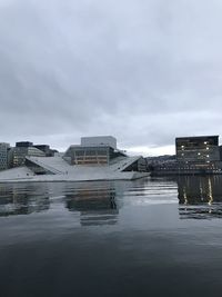 Buildings by lake against sky in city