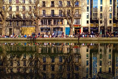 Reflection of people and building on water in city