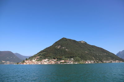 Scenic view of sea and mountains against clear blue sky