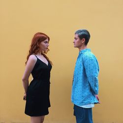 Side view of young couple looking away against wall