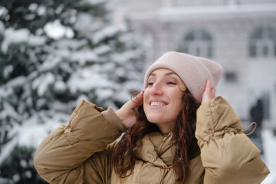 Happy middle age woman catching snowflakes in the city outdoors. relaxed emotional person walking 