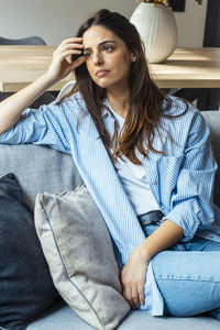 Young woman sitting on sofa at home