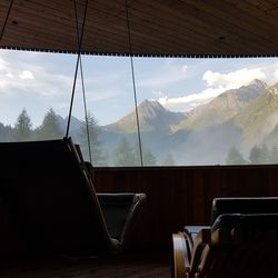 Empty chairs and tables against sky seen through window