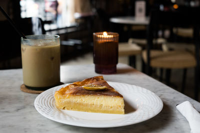 Sliced cheese lemon cake served with iced coffee on the table at the restaurant.