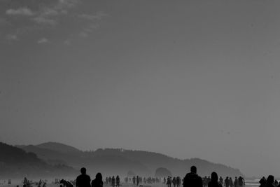 Silhouette people at beach against sky