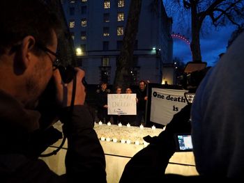 Rear view of man photographing illuminated city at night