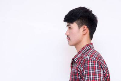 Portrait of young man looking away against white background