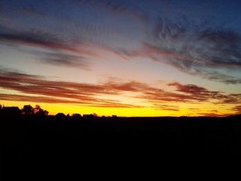 Silhouette landscape against dramatic sky during sunset