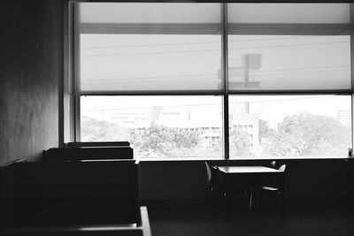 Empty chairs and table against window