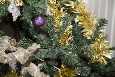 Golden tinsel wrapped around an artificial tree with a ribbon, globe,  and clear star
