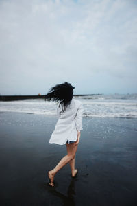 Full length of woman walking on beach against sky