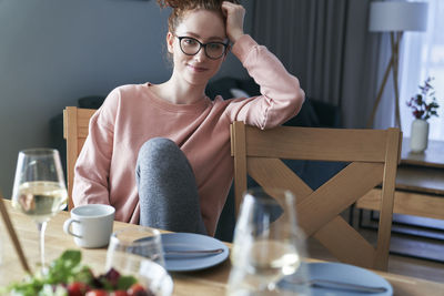 Young woman using mobile phone while sitting on table