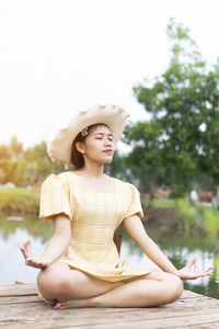 Young woman sitting by lake