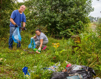 A man and a woman clean up a garbage dump in the nature.a man and a woman clean up a garbage