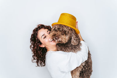 Smiling woman holding dog standing against white background