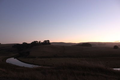 Scenic view of landscape against clear sky during sunset