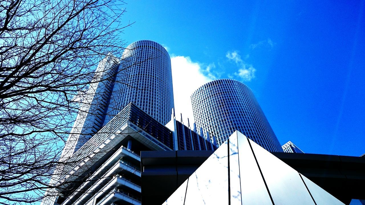 LOW ANGLE VIEW OF MODERN SKYSCRAPER AGAINST BLUE SKY