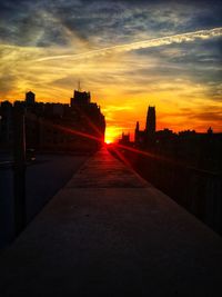 Street amidst buildings against sky during sunset