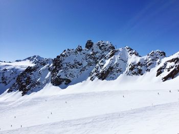 Scenic view of snowcapped mountains against clear blue sky