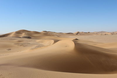 Sand dunes in desert against clear sky