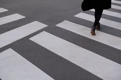 Low section of woman walking on zebra crossing