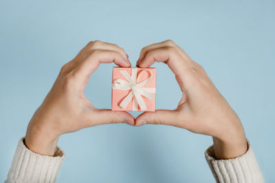 Cropped hand of woman holding gift while making heart shape