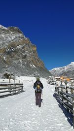 Rear view of people on snowcapped mountains against clear blue sky