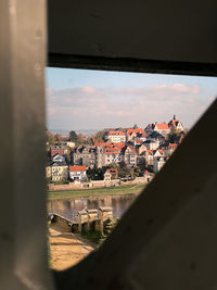 Buildings in city against sky seen through window