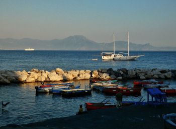 Sailboats moored in sea against clear sky