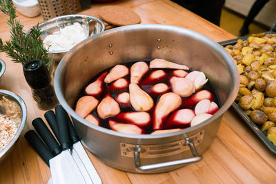 The peeled pear is cooked in red wine in a saucepan on the kitchen table view slightly from above