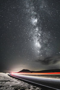 Light trails on road against sky at night