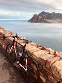 Bicycles on rock by sea against sky